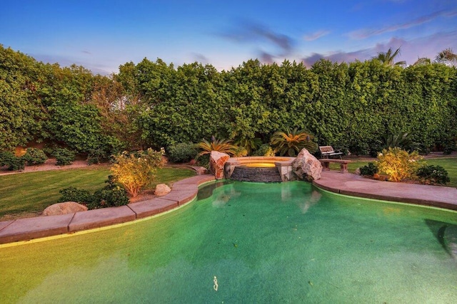 pool at dusk with an in ground hot tub