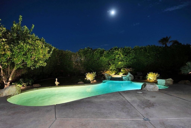 pool at night with a patio area