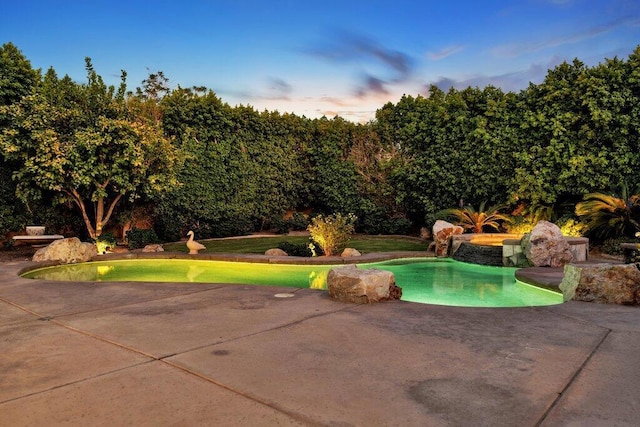 pool at dusk featuring a patio