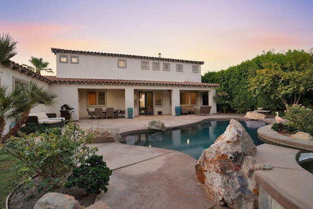 back house at dusk featuring a patio