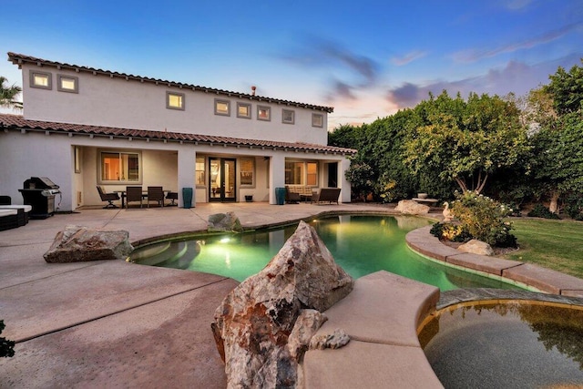 back house at dusk with an outdoor living space and a patio area