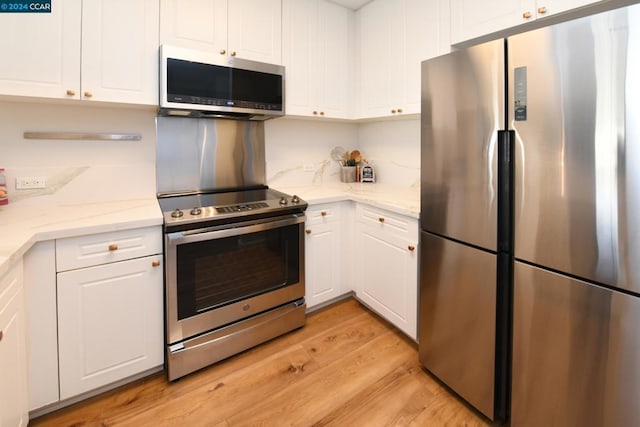 kitchen featuring light stone countertops, appliances with stainless steel finishes, light wood-type flooring, and white cabinetry