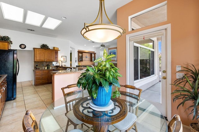 dining area featuring ceiling fan, a skylight, and light tile patterned floors