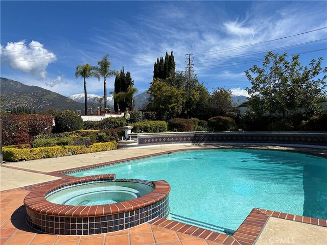 view of swimming pool featuring a mountain view and an in ground hot tub