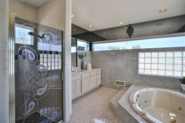 bathroom with shower with separate bathtub, vanity, and tile walls