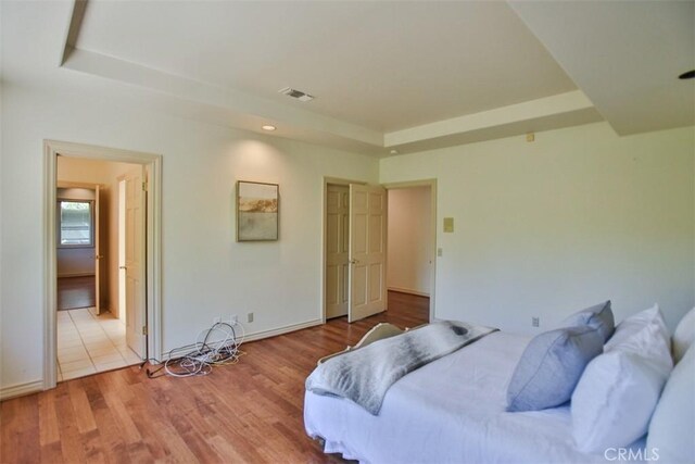 bedroom featuring light hardwood / wood-style floors and a tray ceiling