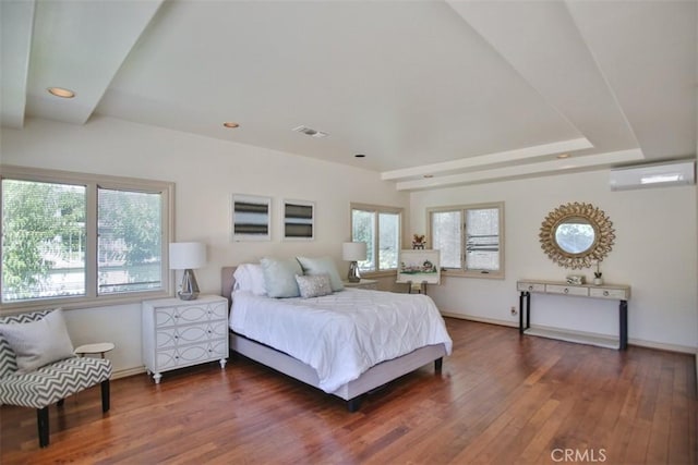 bedroom with a wall unit AC and dark hardwood / wood-style flooring