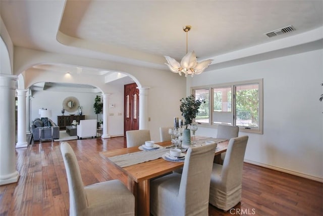 dining room with a raised ceiling, a notable chandelier, and dark hardwood / wood-style flooring