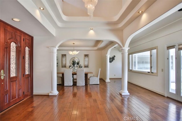 entryway with plenty of natural light, dark hardwood / wood-style flooring, a raised ceiling, and a chandelier