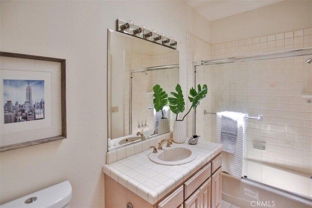 full bathroom with vanity, toilet, and bath / shower combo with glass door