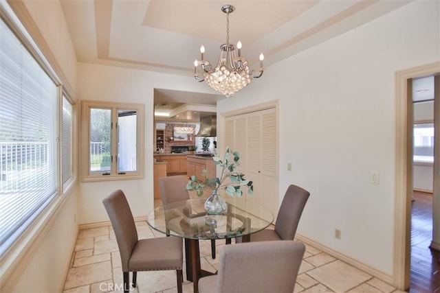 dining room with a raised ceiling, plenty of natural light, and an inviting chandelier