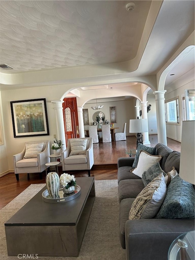 living room with decorative columns, a chandelier, and wood-type flooring