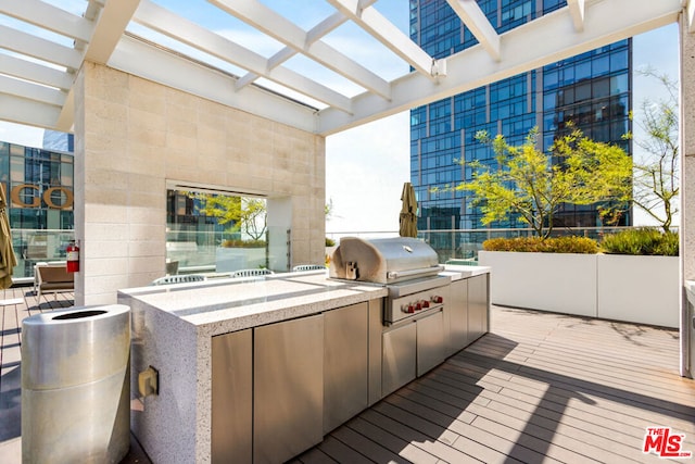 deck with a grill, a pergola, and exterior kitchen