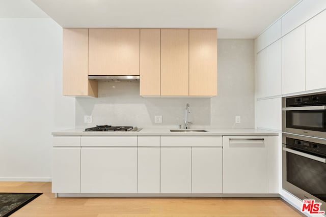 kitchen with dishwasher, sink, light hardwood / wood-style floors, and stainless steel gas cooktop