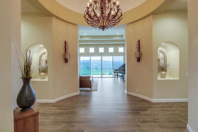 corridor featuring a high ceiling, hardwood / wood-style flooring, and a chandelier