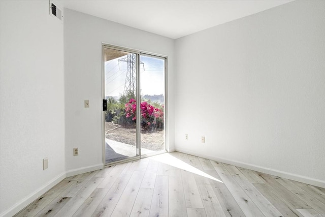 unfurnished room with wood-type flooring, visible vents, and baseboards