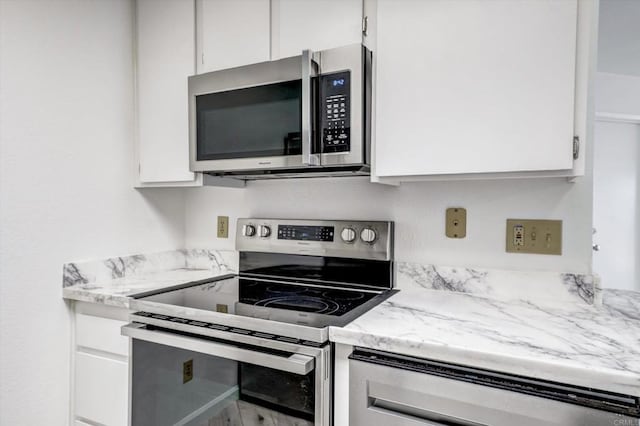 kitchen featuring light stone countertops, appliances with stainless steel finishes, and white cabinets