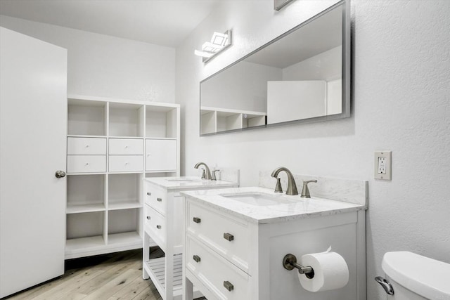 bathroom featuring a textured wall, vanity, toilet, and wood finished floors