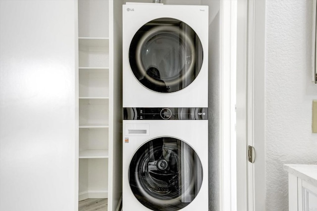 laundry room featuring laundry area, stacked washer / dryer, and wood finished floors