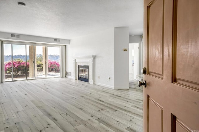 unfurnished living room featuring light wood-style flooring, visible vents, and a tile fireplace