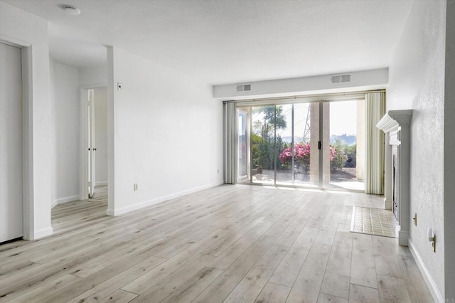 unfurnished living room with light wood-style floors, visible vents, and baseboards