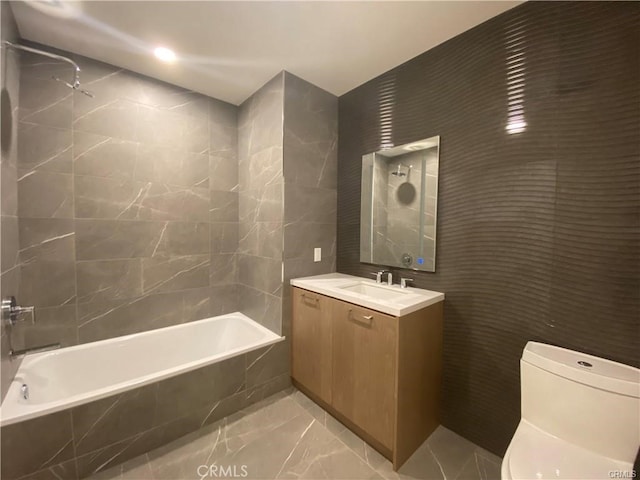 full bathroom with tile walls, vanity, toilet, and tiled shower / bath