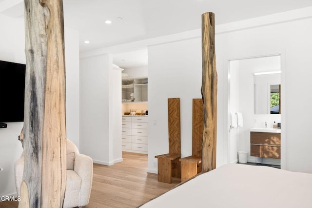 bedroom with light wood-type flooring, connected bathroom, and a walk in closet