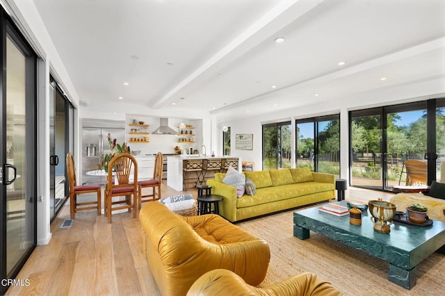 living room featuring beamed ceiling, sink, and light hardwood / wood-style flooring