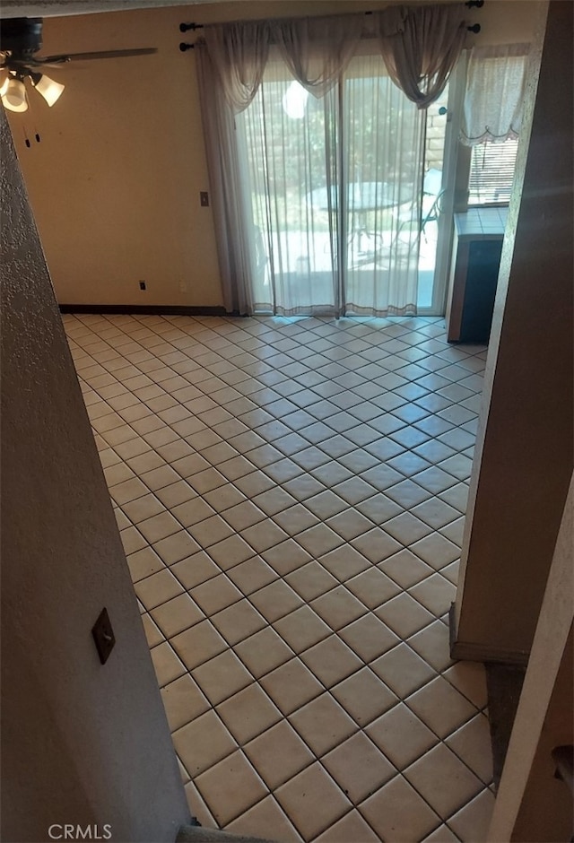 tiled empty room featuring ceiling fan