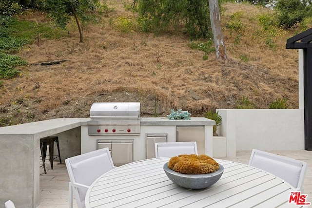 view of patio with area for grilling, exterior bar, and an outdoor kitchen