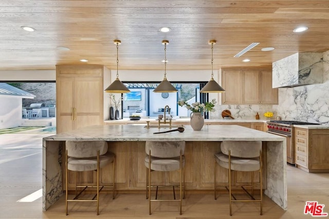 kitchen featuring high end stove, light brown cabinetry, and decorative light fixtures