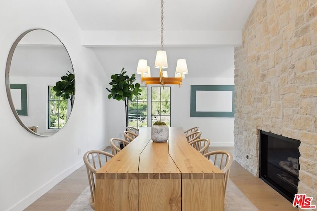 dining space featuring a fireplace, an inviting chandelier, light hardwood / wood-style flooring, and plenty of natural light