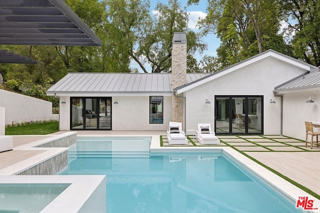 rear view of house featuring a patio and a pool with hot tub