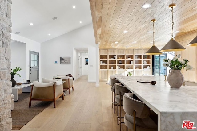 kitchen with light stone countertops, wooden ceiling, hanging light fixtures, high vaulted ceiling, and light hardwood / wood-style floors