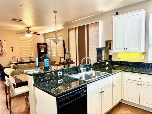 kitchen featuring black dishwasher, sink, white cabinets, kitchen peninsula, and decorative light fixtures