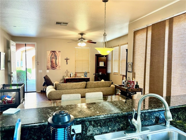 interior space with dark stone countertops, pendant lighting, a textured ceiling, ceiling fan, and sink