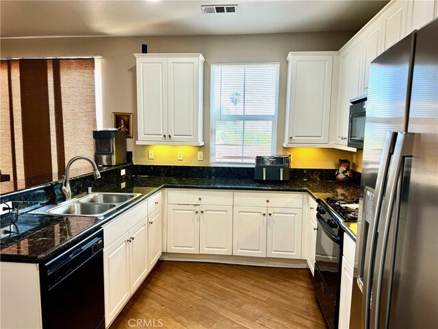 kitchen featuring black appliances, light hardwood / wood-style floors, white cabinetry, and sink