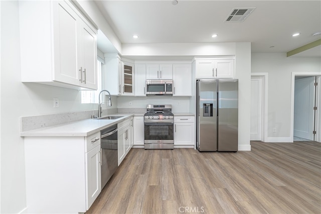 kitchen with light hardwood / wood-style floors, appliances with stainless steel finishes, sink, and white cabinetry