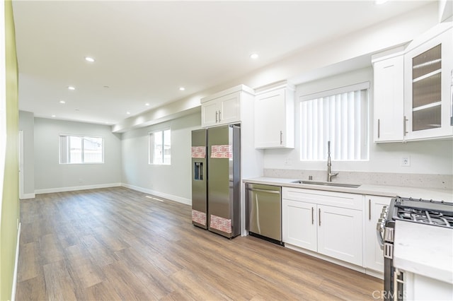 kitchen featuring white cabinets, stainless steel appliances, light wood-type flooring, and sink