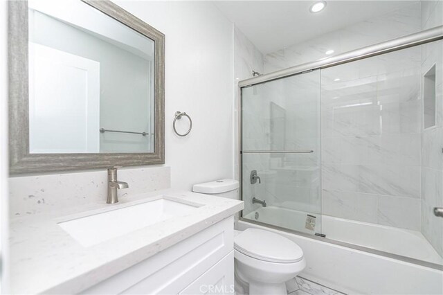 full bathroom featuring enclosed tub / shower combo, vanity, and toilet