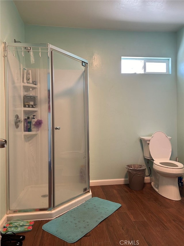 bathroom featuring toilet, an enclosed shower, and wood-type flooring