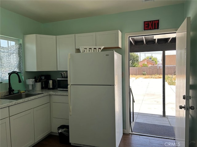 kitchen with sink, dark wood-type flooring, white cabinets, and white refrigerator