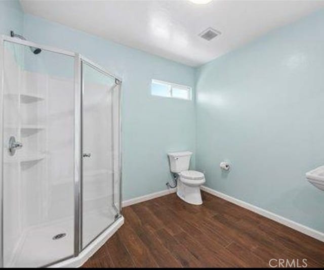 bathroom with toilet, hardwood / wood-style flooring, and an enclosed shower