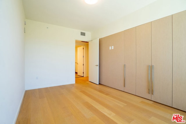 unfurnished bedroom with a closet and light hardwood / wood-style floors