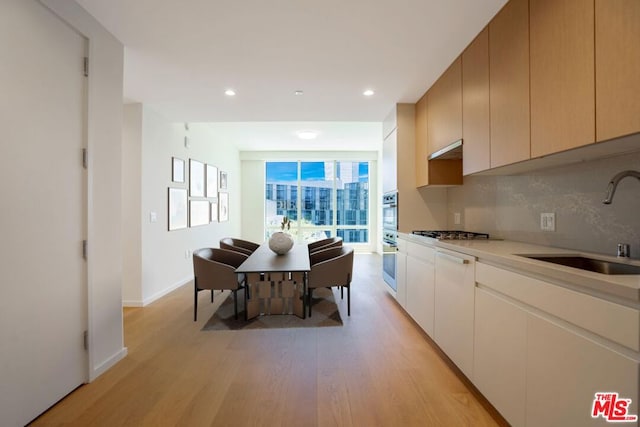 kitchen with light hardwood / wood-style floors, sink, stainless steel gas cooktop, and tasteful backsplash