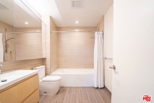 full bathroom with shower / bath combo with shower curtain, tile walls, toilet, and vanity