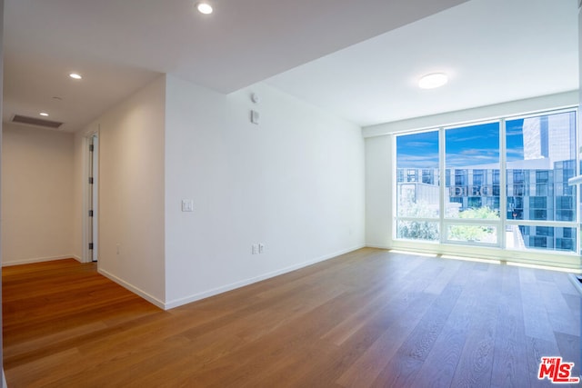 unfurnished room featuring floor to ceiling windows and hardwood / wood-style flooring