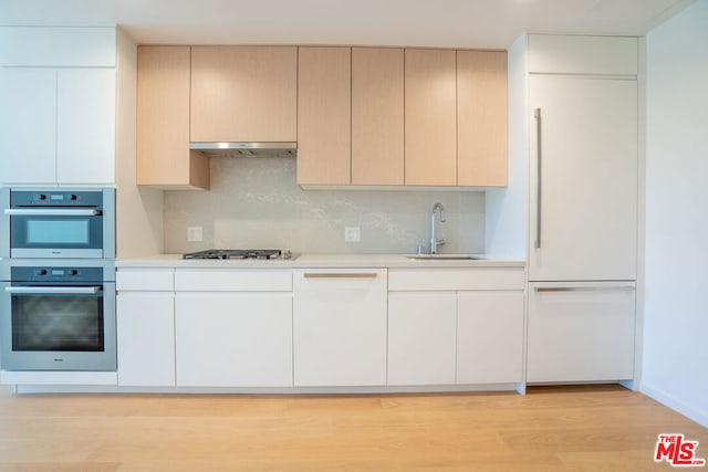 kitchen with appliances with stainless steel finishes, light hardwood / wood-style flooring, backsplash, and sink