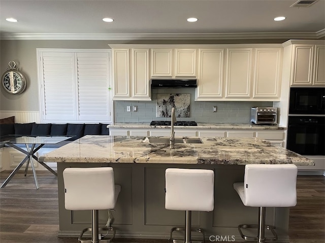 kitchen with black appliances, a kitchen island with sink, and a kitchen bar