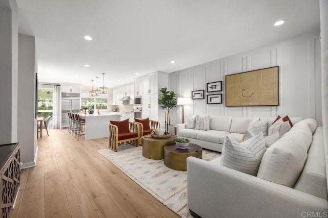 living room featuring a decorative wall, recessed lighting, and light wood-style floors